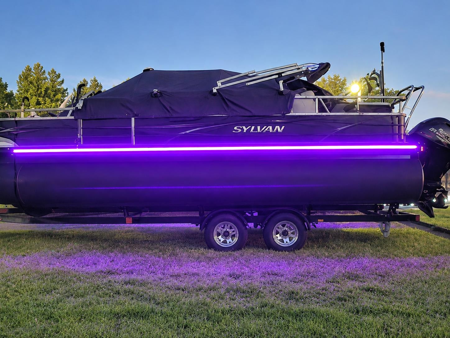 Sylvan boat with purple LED lights on a grassy area
