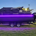 Purple boat with LED lights on a trailer, branded 'Sylvan', against a clear blue sky.