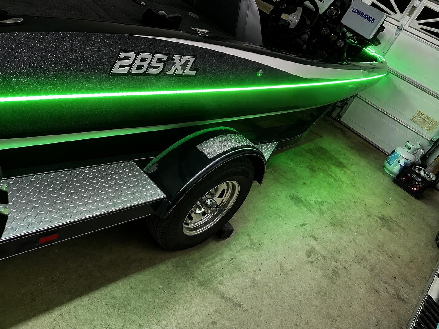 Green boat with '285 XL' marking on a trailer inside a garage.