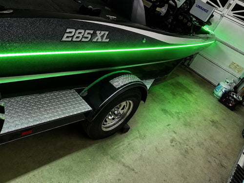 Green boat with '285 XL' marking on a trailer inside a garage.