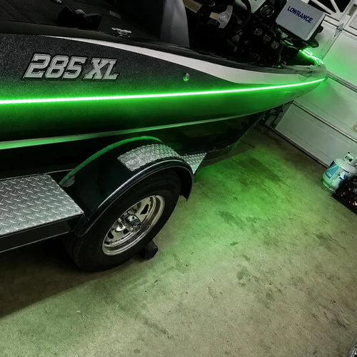 Green boat with '285 XL' on a trailer in a garage.
